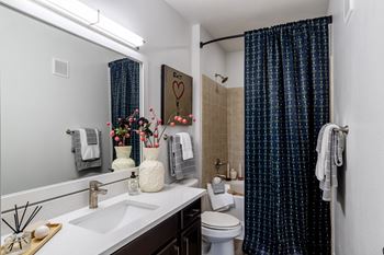 Bathroom with toilet and bathtub with curtain at Grand Villas at Cinco Ranch, Katy, TX
